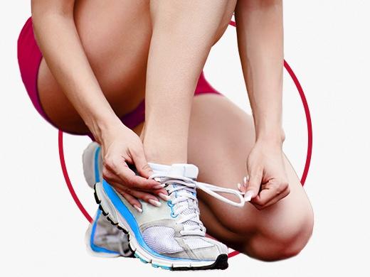 Kvinna i shorts och vita gymnastikskor som knyter skorna